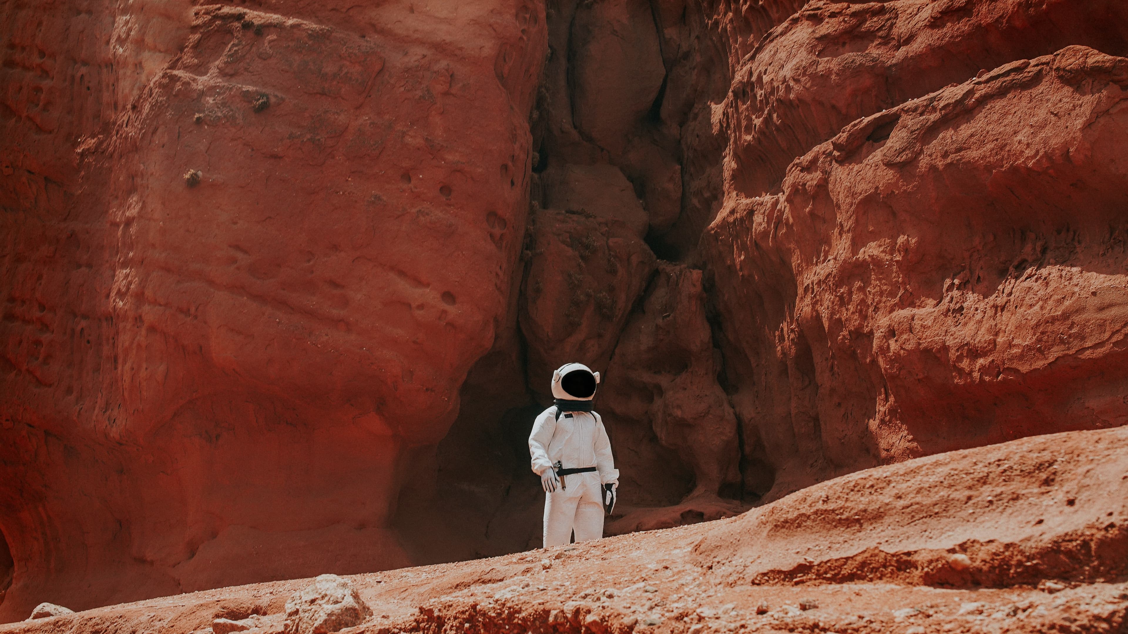 An astronaut standing in a canyon of red rock